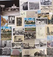 Full view of the postcard collection laid out displaying a variety of images including animals, harbor scenes, architecture, aerial views, and animated illustrations.