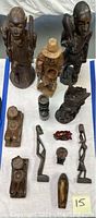 Top view of multiple carved wooden tribal and animal figures on white surface