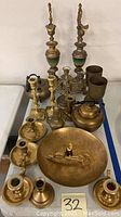 Overall view of the collection including candleholders, teapots, cups, large etched dish, and candle snuffer scissors on top