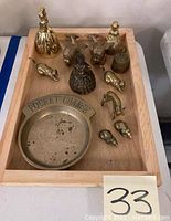 Top-down photo showing the full set of brass figurines and coin dish arranged on a wooden tray, which is not included with the lot.
