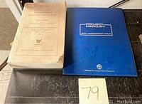 Two items: a thick paperback government report on the left and a blue hardcover stamp album on the right.