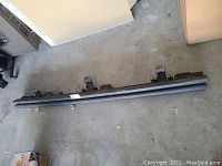 Black metal Jeep Wrangler rock slide with mounting brackets, placed on garage floor.