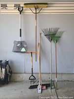Photo showing the full assortment of six outdoor tools including snow shovel, brooms, and rakes lined up against a wall.