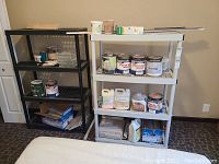Photo showing two shelving units side by side, one black and one light gray, filled with various paint and cleaning supplies (not included).