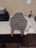 Stack of men's shirts along with a gray sweater laid on a table
