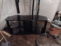 Front view of black media shelf with three dark glass shelves