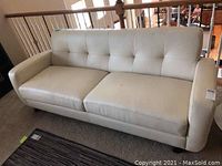 Front view of white leather sofa showing tufted backrest and seat cushions