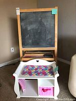 Photo showing the doll changing table in front with cushioned changing pad and fabric bins, and chalkboard easel behind with visible chalkboard surface and drawer.
