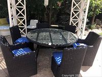 Full set of round wicker style table and six chairs under pergola