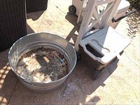 Galvanized metal tub placed on ground showing some debris and wear inside