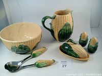 Full set with salad bowl, service spoon and fork, beverage pitcher, butter dish with lid, and salt and pepper shakers all showing corn cob design and arrangement.