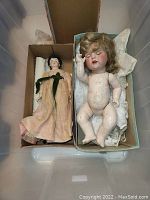 Photo of two antique dolls in shoeboxes, one clothed and one undressed, showing their condition and size.