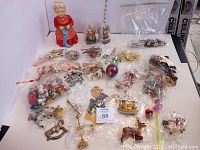 Overview photo of Christmas ornaments including many in plastic bags, miscellaneous small ornaments, two merry-go-round ornaments, and a vintage Mrs. Claus figurine on a white surface.
