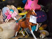 Photo showing brown horse figurine and blonde doll in a plastic bag, with a pink Polly Pocket compact visible
