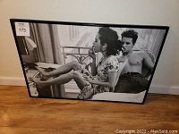 Front view of the framed art print showing a black and white photo of a woman and a man.