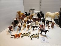 Full display of approximately 30 horse figurines including large cream colored Breyer model, various sizes and colors, and jockey mounted race horses.