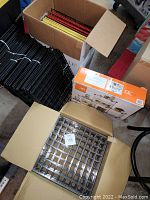 Wide view of multiple boxes containing stacked wire storage cubes in black, yellow, red, and silver, along with a box of connectors and a separate box with metal cubes.