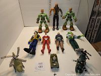 Photo showing all figures and toy vehicles in the lot, including action figures standing and lying down, two helicopters, jeep, and plane.