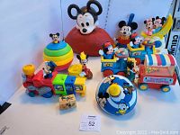 Wide view showing the full lot of colorful vintage Mickey Mouse toys on white background including train, ball, popcorn popper, spinner top, musical crib items, and figures.