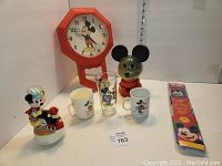 Full lot showing all Mickey Mouse items: musical train figurine, mugs, glass, clock, gumball machine, and packaged flag.