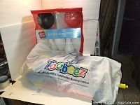 Photo of the Toobeez construction building system in its carrying/storage bag and the PlayDay Jumbo Bowling Set in its red and clear plastic bag showing bowling pins and balls inside.