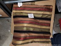 Single folded pillow cover with horizontal multicolor stripes in a cardboard box.