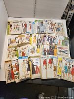 Assorted vintage and modern sewing pattern envelopes laid flat showing a variety of women's fashions including dresses, skirts, and blouses.