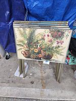 Stack of five vintage metal TV trays showing floral basket print on top tray