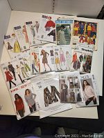 Photo shows assortment of vintage and modern sewing patterns from brands Vogue, McCalls, Kwik Sew, and others with various women's fashion styles on covers.