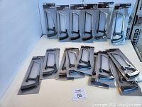 Photo showing 15 unopened 6-inch hacksaws laid out on a flat surface.