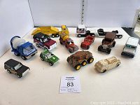 Full view of 11 vintage toy vehicles in varied condition arranged on white surface with ruler in background for scale.
