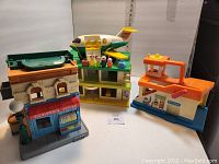 Full view of four vintage play sets including Little People Jet Liner, Playskool Holiday Inn, Tonka Airport, and Sesame Street.