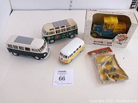 Group photo showing three Volkswagen van toys, the 1918 Runabout bank in original box, and the sealed pack of vintage transport vehicles.