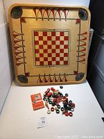 Vintage wooden Carrom board with pieces spread in front and rule book included, showing overall condition and size.