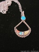 Front view of the pendant showing twisted silver rope frame and multicolor stone inlay, turquoise accent at top, and attached silver chain.