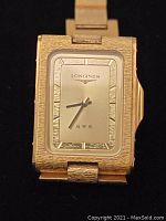 Front view of Longines QWR wristwatch with gold tone rectangular case and silver dial.