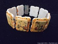 Photo of the bracelet showing the hand-painted tile panels connected and forming a circle with visible front artwork.