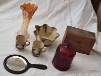 Photo of entire lot showing the glass vase, Frankoma mugs and pottery bowl, red glass jar, wooden box, and magnifying mirror