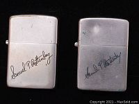 Two silver tone Zippo lighters side by side with Samuel P. Rotenberg signature, one lighter visibly dented.