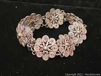 Photo showing the vintage silver bracelet laid flat displaying the linked floral filigree design.