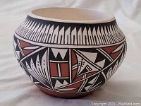 Pottery bowl with geometric and tribal painted design shown from front angle