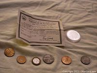 Image showing six assorted smaller coins alongside a certificate of authenticity and the Silver Buffalo coin in protective casing.