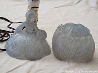 View of the lamp base with the frosted glass lady figurine holding a textured ball and the matching frosted glass dome-shaped shade with petal and floral pattern details.