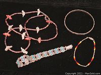 Photo of necklace with bird-shaped pendants, silver bangle, multicolor bead bracelet, and turquoise inlay bracelet.