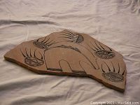 Photo of the full pottery shard showing central bear figure and surrounding oval designs with geometric patterns.