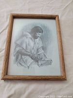 Framed black and white print of a man reading or examining an object, shown from one angle.