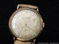 Front of Bulova watch showing worn dial with gold-tone numbers and hands, and small seconds dial.