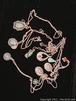 Photo of tangled Native American sterling silver jewelry including necklaces with turquoise and coral pendants and floral design earrings.