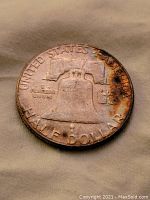 Reverse side of the 1953 silver half dollar coin showing the Liberty Bell with some discoloration and wear.