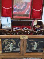 Exterior front view showing carved fretwork, lacquer panels with figures, central mirror and red felt interior